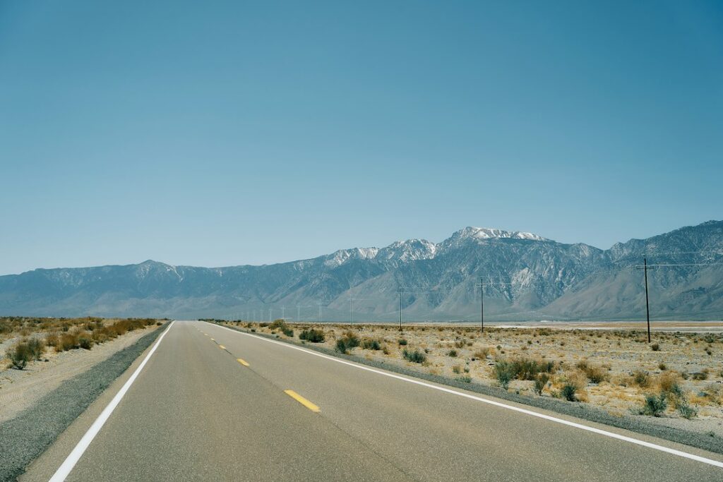 Illustrative desert highway and mountains photo by Bastian Pudill / Unsplash; not a documented view of Red Mountain, Randsburg or the Ridgecrest road trip.