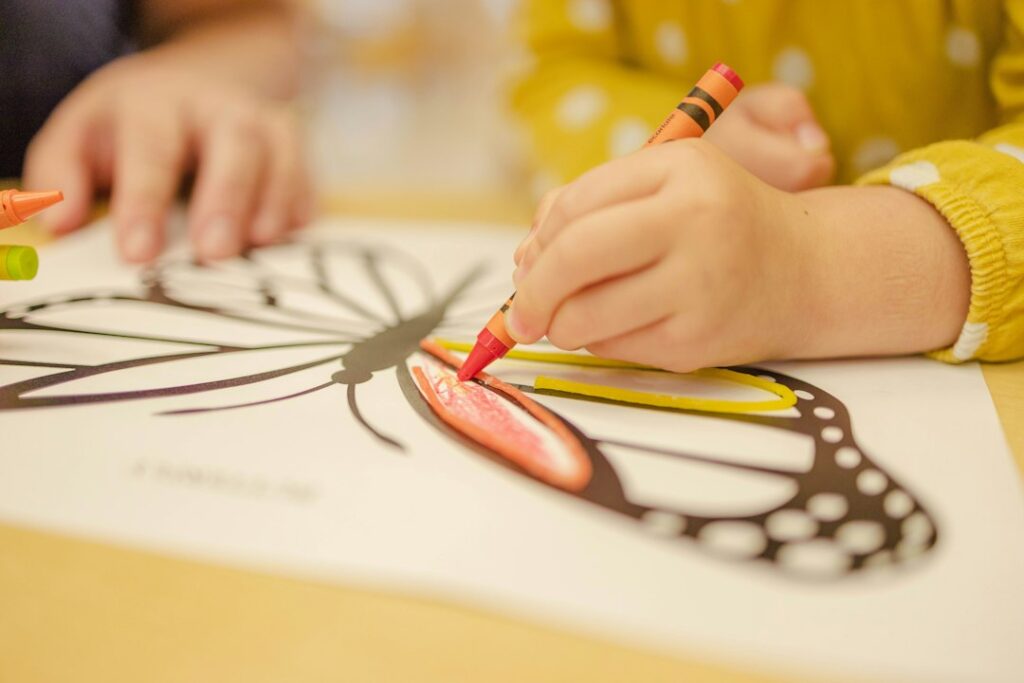 Illustrative child coloring a butterfly, not a photograph of students or programs at Prunedale Preschool