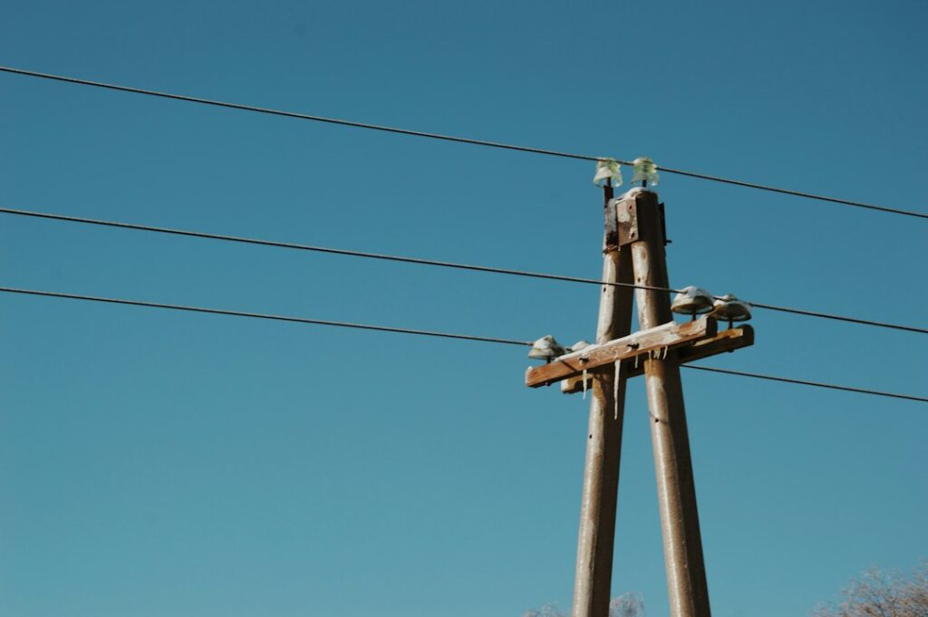 Electrical utility pole and wires against a blue sky. Illustrative photograph by Timofey Radkevich on Unsplash; not a specific California extension project.