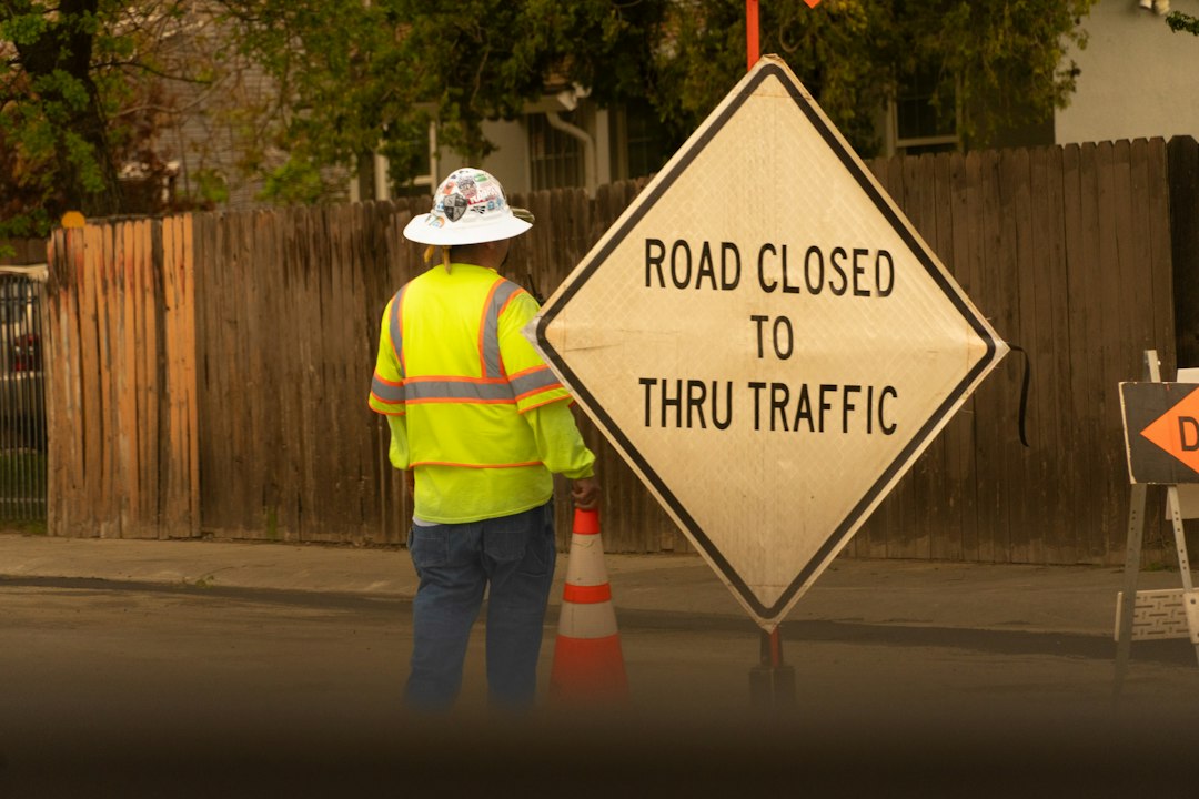 Road construction worker standing beside a road-closed sign in a highway work zone