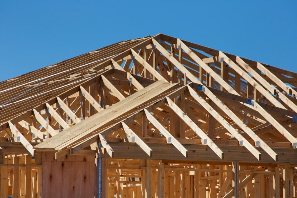 Timber-framed house under construction with roof trusses; illustrative construction photograph, not a documented California owner-builder project
