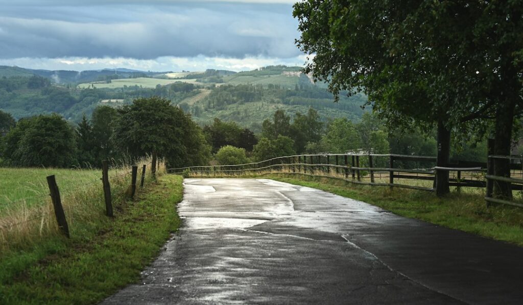 Illustrative wet rural road, not a photograph of flooding in Chualar