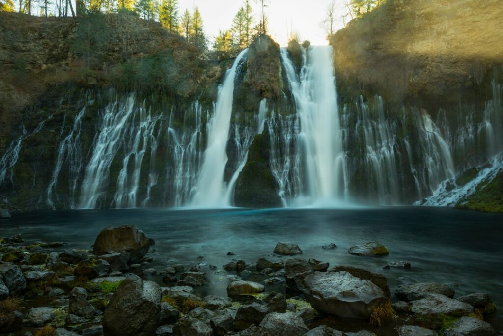 Waterfall and wooded cliffs at McArthur-Burney Falls Memorial State Park, California. Photo by Joel Protasio / Unsplash.