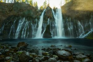 Waterfall and wooded cliffs at McArthur-Burney Falls Memorial State Park, California. Photo by Joel Protasio / Unsplash.