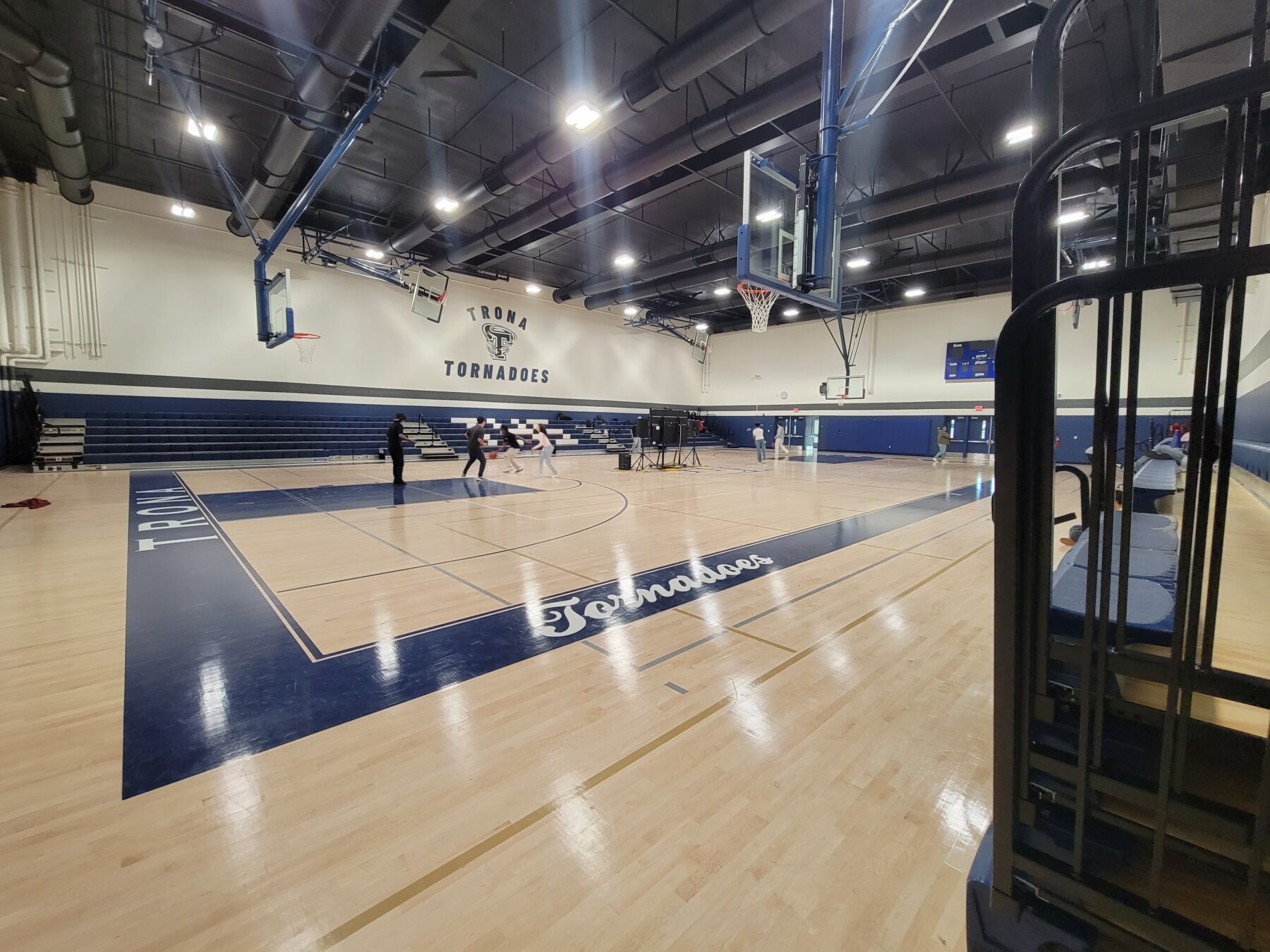 New Trona High School interior gymnasium with a polished basketball court, seating and Tornadoes mascot.