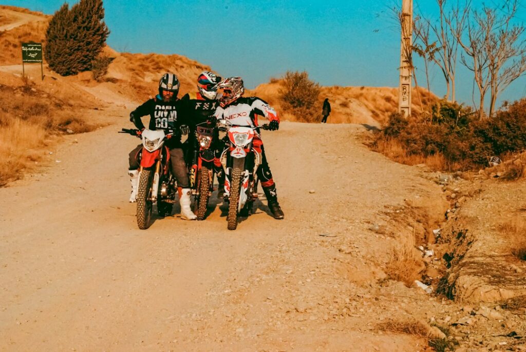 Two people riding off-road motorcycles on dirt terrain, photograph by Nima Mot / Unsplash. Illustrative only, not Carnegie SVRA or the October 2026 California State Parks hearing.