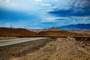 Illustrative paved road and desert mountains by Amelia Hollis / Unsplash; not a verified Red Mountain parcel or access road.