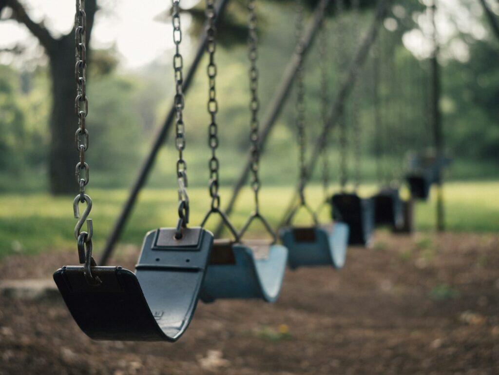 Illustrative playground swings by Aaron Burden, not the actual equipment at Manzanita Stuart or Lincoln Cunningham parks.