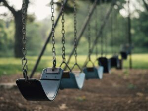 Illustrative playground swings by Aaron Burden, not the actual equipment at Manzanita Stuart or Lincoln Cunningham parks.
