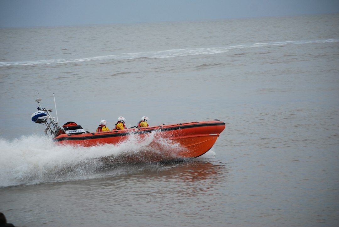 Rescue crew in an orange boat wearing helmets and life jackets, illustrative image